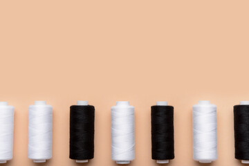 Black and white thread spools on color background