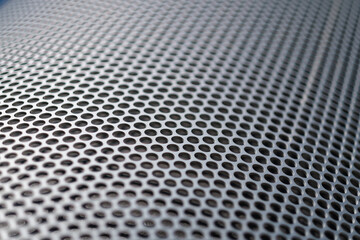 A titled view of a steel panel on a secure enclosure, showing a seemingly infinite view of precisely drilled circular cutouts going into the distance.