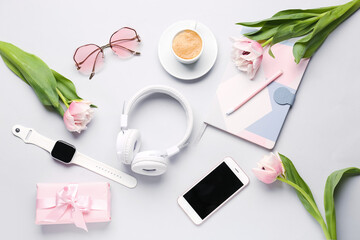 Composition with modern gadgets, gift, cup of coffee and tulip flowers on light background