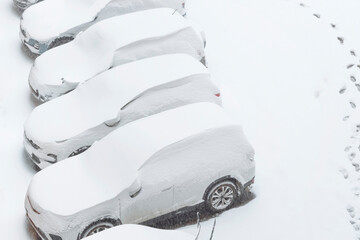 Cars covered with snow parked in the yard of a residential building