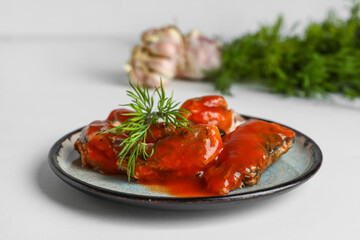 Plate with canned fish in tomato sauce and dill on white table