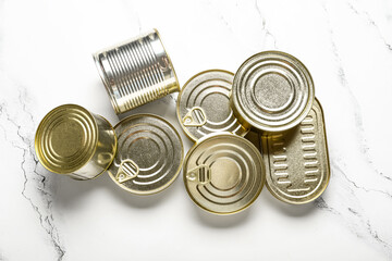 Different tin cans with fish on white marble table
