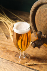 Oak barrel and glass of cold beer on wooden background
