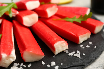 Slate board with tasty crab sticks on table, closeup © Pixel-Shot