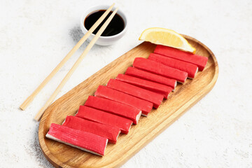 Wooden board with tasty crab sticks on light background © Pixel-Shot