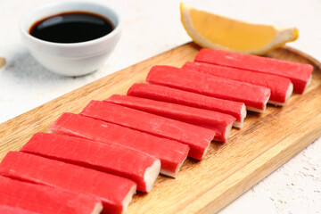 Wooden board with tasty crab sticks on light background, closeup © Pixel-Shot