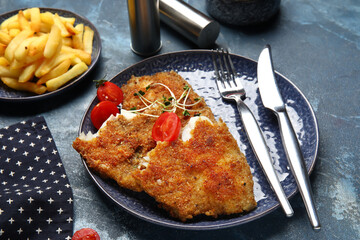 Plate of tasty fried codfish on blue background
