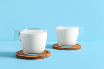 Glass cups with fresh milk on blue background