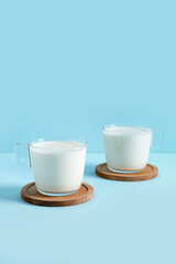Glass cups with fresh milk on blue background