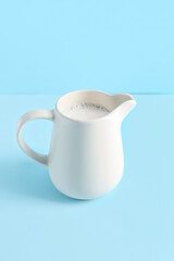 Jug with fresh milk on blue background