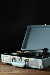 Record player with vinyl disk on dark wooden background