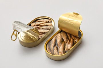 Opened tin cans with sprats in oil on grey background