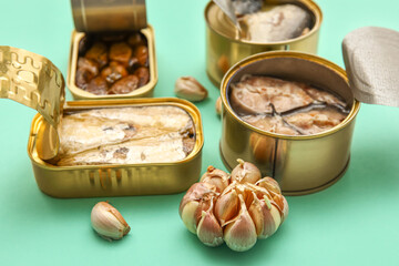 Opened tin cans with different fish and mussels on turquoise background