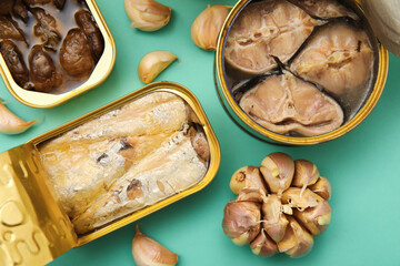 Opened tin cans with different fish and mussels on turquoise background