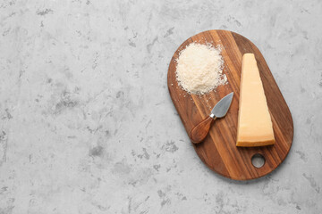 Fototapeta na wymiar Wooden board with tasty Parmesan cheese on grunge background