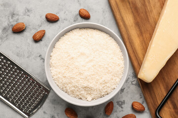 Bowl with tasty Parmesan cheese on grunge background