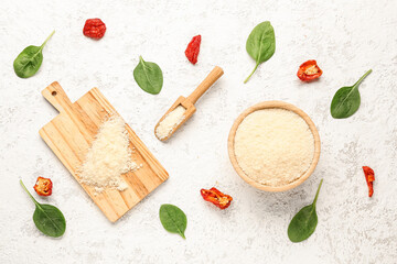 Composition with tasty grated Parmesan cheese and leaves of spinach on light background