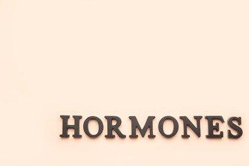Word HORMONES on beige background