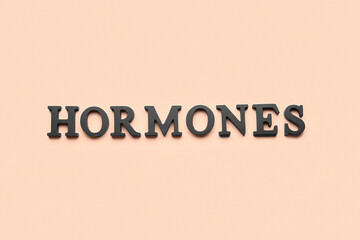 Word HORMONES on beige background
