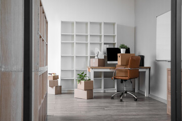 Workplace with cardboard boxes in office on moving day, view through folding screen
