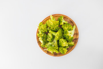 Simple boiled broccoli in a wooden plate and isolated with the white background. Organic boiled broccoli in a wooden plate. Healthy eating concept.