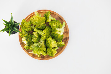 Simple boiled broccoli in a wooden plate and isolated with the white background. Organic boiled broccoli in a wooden plate. Healthy eating concept.