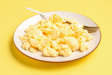 Plate of delicious scrambled eggs on yellow background