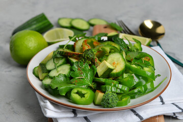 Plate of salad with green vegetables on grey grunge background