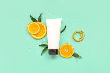 Tube of cosmetic product with orange slices and leaves on turquoise background