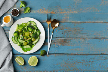 Plate of salad with vegetables and ingredients on blue wooden background
