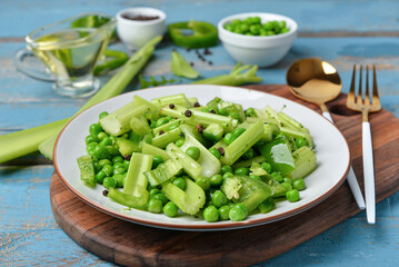 Board with plate of salad and ingredients on blue wooden background