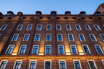 The wall of an old brick house in the evening with lighting.