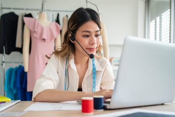 Fashion designer woman talking smart phone and using laptop with digital tablet computer in modern studio