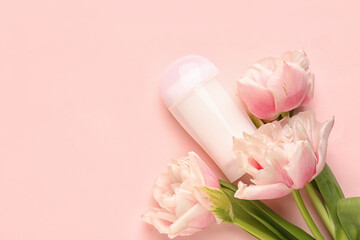 Deodorant bottle and flowers on pink background