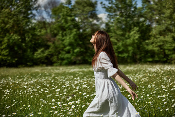portrait of a free woman in a light dress in a chamomile field against the backdrop of hills enjoying nature