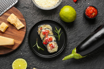 Plate with tasty baked Eggplant Parmesan and ingredients on dark background