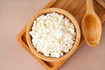 Bowl with tasty cottage cheese on beige background