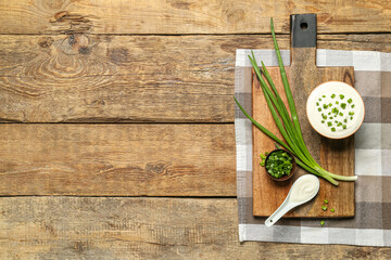 Bowls of tasty sour cream with green onion on wooden background