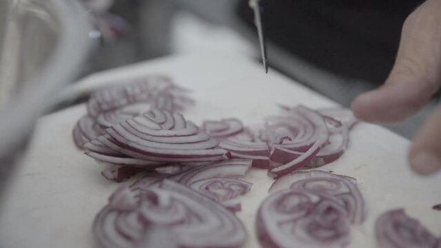 Cutting small pieces of red onion on a white kitchen board in slowmotion LOG