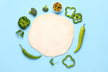 Raw dough and ingredients for preparing vegetable pie on blue background