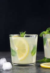 lemonade or cocktail with lemon and mint on a black background. Summer refreshing drinks. Copy space.