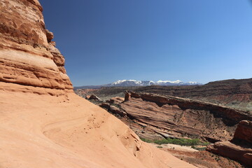 Breathtaking views of the desert valley below with the majestic snowcapped La Sal Mountains in the background photo taken from a hiking trail a the Arches National Park Moab Utah
