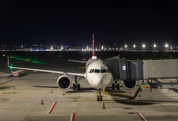 The plane stands at the boarding bridge at night