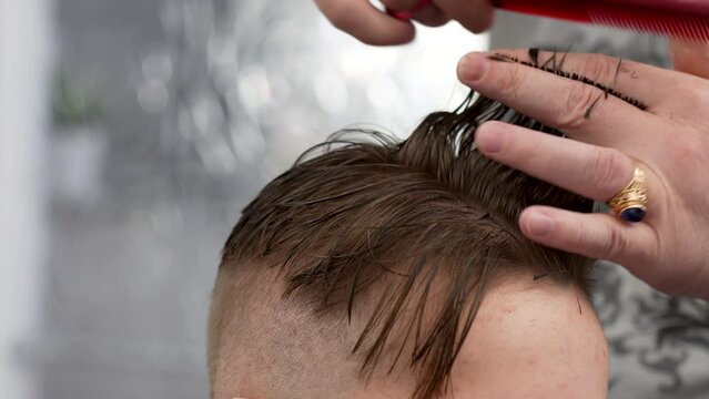 Close-up of barber doing haircut at hair salon or barber shop