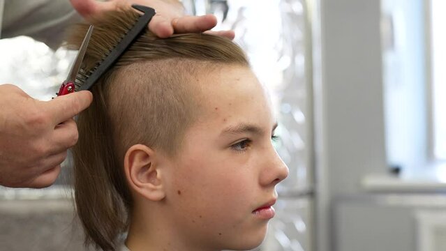 Close-up of barber doing haircut at hair salon or barber shop