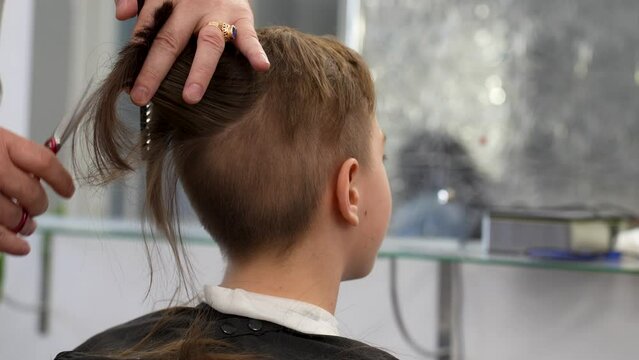 Close-up of barber doing haircut at hair salon or barber shop