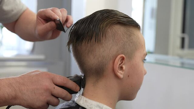 Close-up of barber doing haircut at hair salon or barber shop
