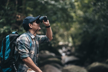 Fototapeta premium Hikers use binocular to see animals and view landscape with backpacks in the forest. hiking and adventure concept.