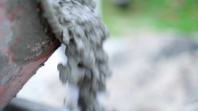 Ready-made concrete mortar is poured from a small coronal concrete mixer, close-up. Pouring concrete