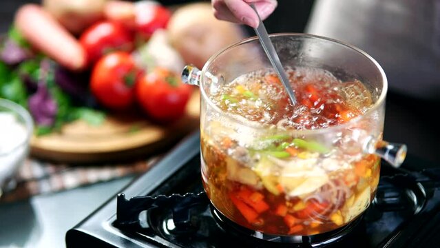 stirring of vegetable soup in pot with ladle	